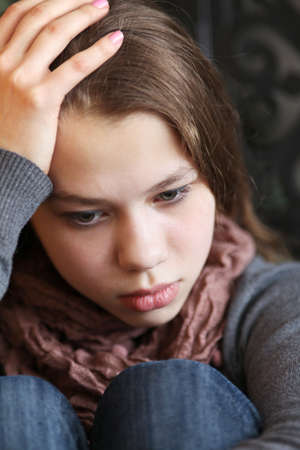 girl teenager sitting on the floor clasping his knees, and in thoughtの写真素材
