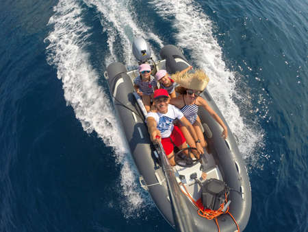 family with children sailing on an inflatable motorboat in the seaの写真素材