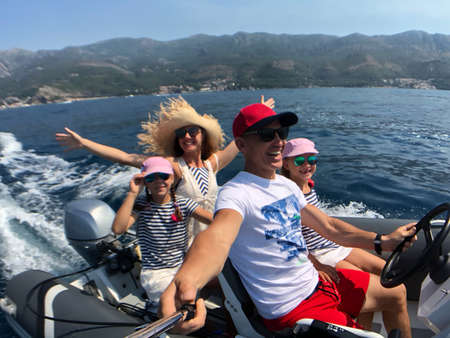 family with children sailing on an inflatable motorboat in the seaの写真素材