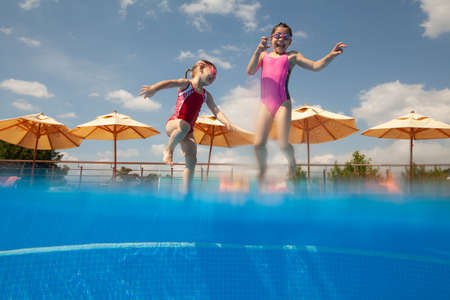 little girls having fun jumping in the pooll.の写真素材