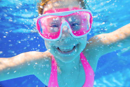 little girl having fun with bubbles in the pooll.Underwater photo.の写真素材