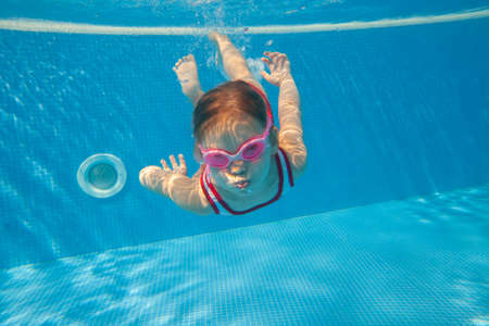 little girl swimming in pool underwater.の写真素材