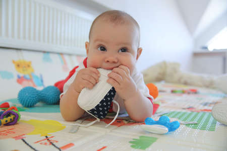 newborn baby chewing shoes on the floor aloneの写真素材