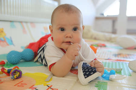 newborn baby chewing shoes on the floor aloneの写真素材