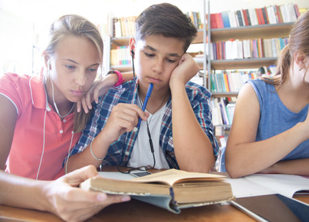 group of students engaged in learning at the desk in the libraryの写真素材
