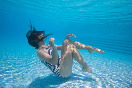 Teenager girl having fun with bubbles in the pooll.Underwater photo.の写真素材