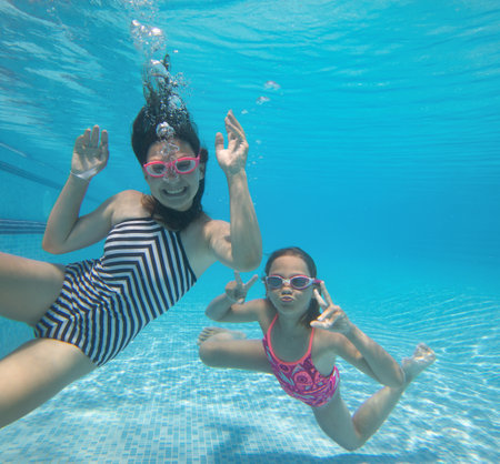 little girls having fun with bubbles in the pooll.Underwater photo.の写真素材