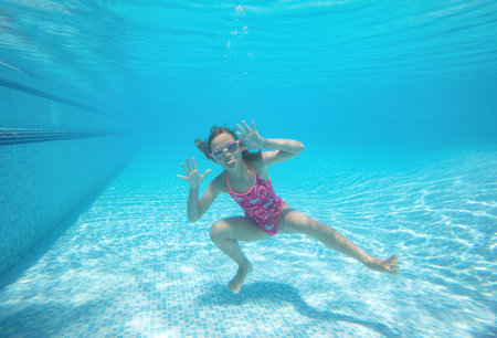 little girl having fun with bubbles in the pooll.Underwater photo.の写真素材