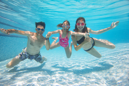 underwater photo of big family with little kids swimming in poolの写真素材