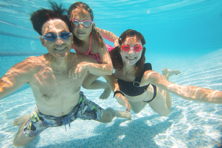 underwater photo of family with little kids swimming in poolの写真素材