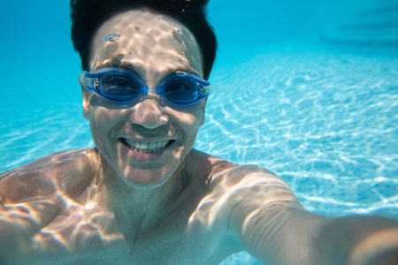 Positive man enjoying in the swimming pool. underwater photo.の写真素材