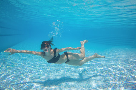 young woman dives into the swimming pool with bubbles. underwater photoの写真素材
