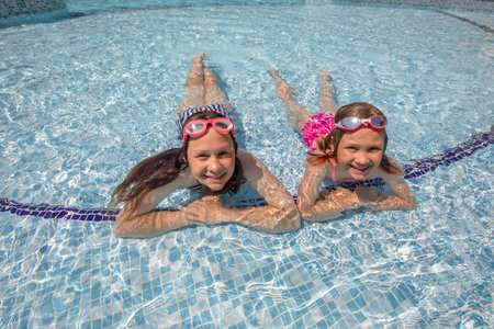 Two teenager girs having fun in swimming pool on resortの写真素材