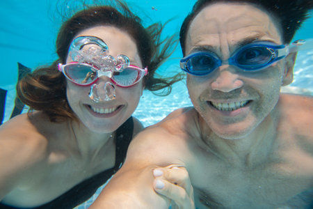 underwater photo of yiung couple swimming in poolの写真素材