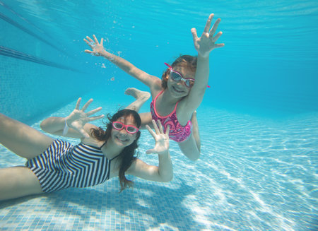 Two teenager girs l having fun with bubbles in the pooll.Underwater photo.の写真素材