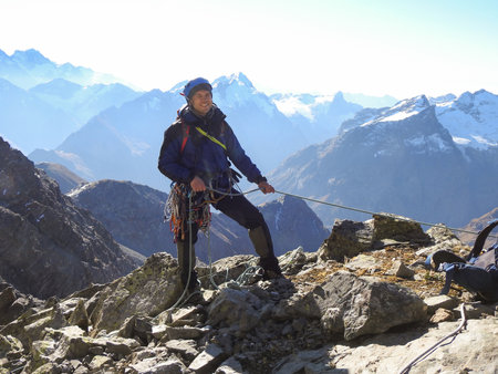 mountainee rclimbing on the top of a mountain in the background of the landscape of snowy mountainsの写真素材