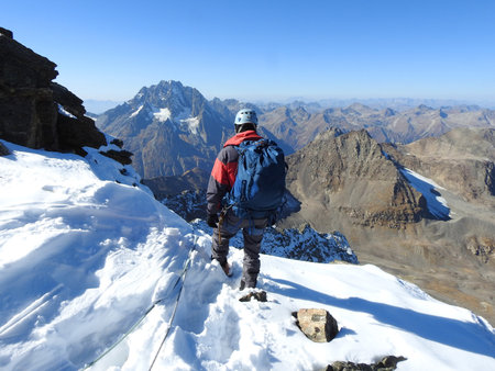 mountaineer with ice ax stands on the top of a mountain in the background of the landscape of snowy mountainsの写真素材
