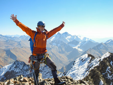 mountaineer with ice ax stands on the top of a mountain in the background of the landscape of snowy mountainsの写真素材