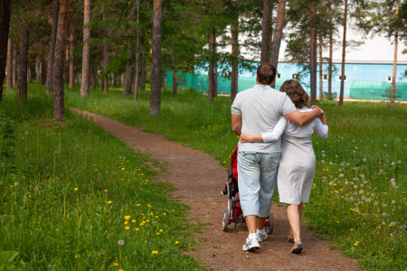 Lovely couple walking with carriage in summer park background. back viewの写真素材