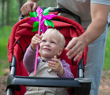 Portrait of little boy in pram playing with toy in father backgroundの写真素材