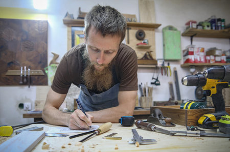 professional carpenter works in his workshop on wooden products.