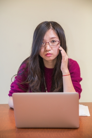 Portrait of young woman with glasses, book and laptopの写真素材