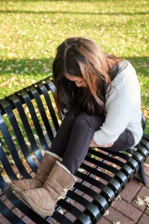 lonely young woman sitting on a steel benchの写真素材