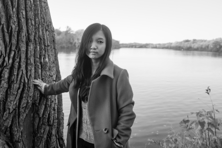 Portrait of young woman leaning against a tree next to a riverの写真素材