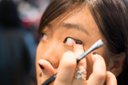 Young Asian woman applying eye liner with a small brushの写真素材