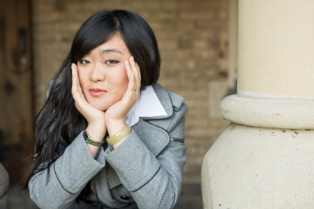 Young woman leaning forward next to stone pillarsの写真素材