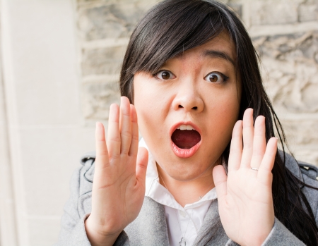 Portrait of attractive young woman looking surprised and screaming out loudの写真素材