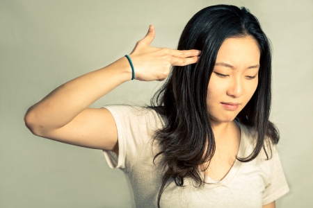 Depressed young woman hand signals suicide, with fashion tone and backgroundの写真素材
