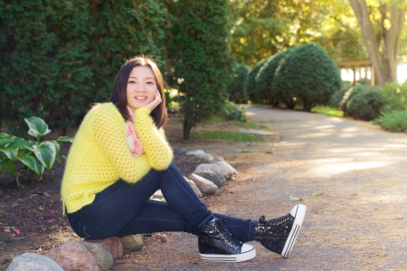 Young woman sitting next to a road looking happyの写真素材