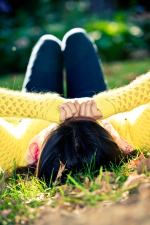 Unique top view of young woman laying in grass with a bunch of fallen leafsの写真素材