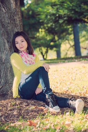 Portrait of happy looking woman sitting against a treeの写真素材