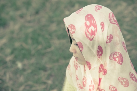 Beautiful young woman with skull covering head and face in sunshineの写真素材