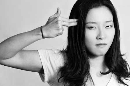 Portrait of depressed young woman hand signals suicide, black and white styleの写真素材