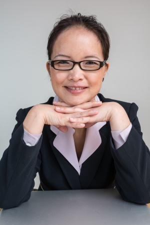 Professional woman in business suit with a closed laptop on deskの写真素材