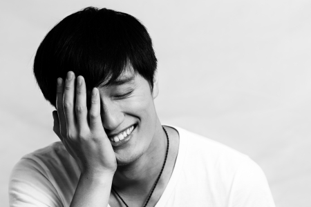 Portrait of young man covering his face and smiling, black and white styleの写真素材