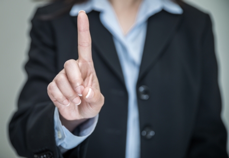 Professional woman in business suit shaking one finger and denying on grey background の写真素材