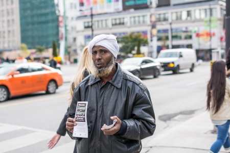 TORONTO, ON, CANADA - OCTOBER 30:  African American man holding brochure about Christianity and walking down a street, in Toronto Canada on October 30, 2013のeditorial素材