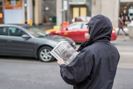 TORONTO, ON, CANADA - OCTOBER 30: Man in coat reading news paper on the side of a street, in Toronto Canada on October 30, 2013のeditorial素材