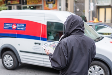 TORONTO, ON, CANADA - OCTOBER 30: Man in coat reading news paper on the side of a street, in Toronto Canada on October 30, 2013のeditorial素材
