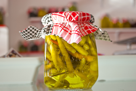 Marinated and pickles vegetables - hot peppers, tomatoes, cucumbers in a glass jars with fabric coversの写真素材