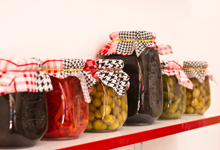 Marinated and pickles vegetables - hot peppers, tomatoes, cucumbers in a glass jars with fabric coversの写真素材