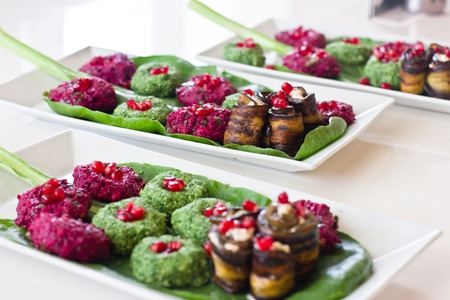 Rolls of eggplant with a filling of walnuts, Georgian snack "pkhali" of spinach and beet with herbs and pomegranate seeds, on sheet of chardの写真素材