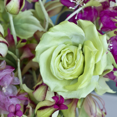 Bouquet of yellow roses with red flowers with buds in vase on a white tableの写真素材
