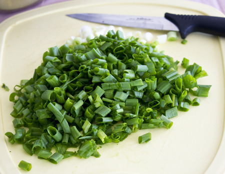 Sliced green onion on a cutting board with the knifeの写真素材