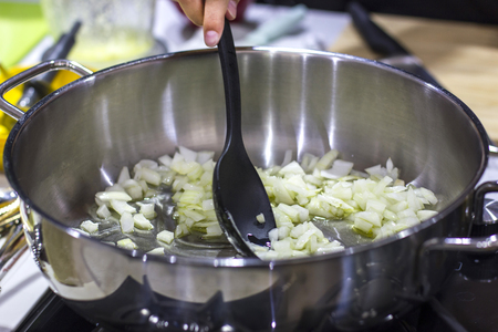 Hand fry onions in a large saucepan, stirring it with black spoonの写真素材