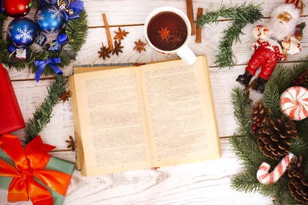 Christmas background. Girl reading book and drinking tea near gift boxes and pine fir. New Year moodの写真素材